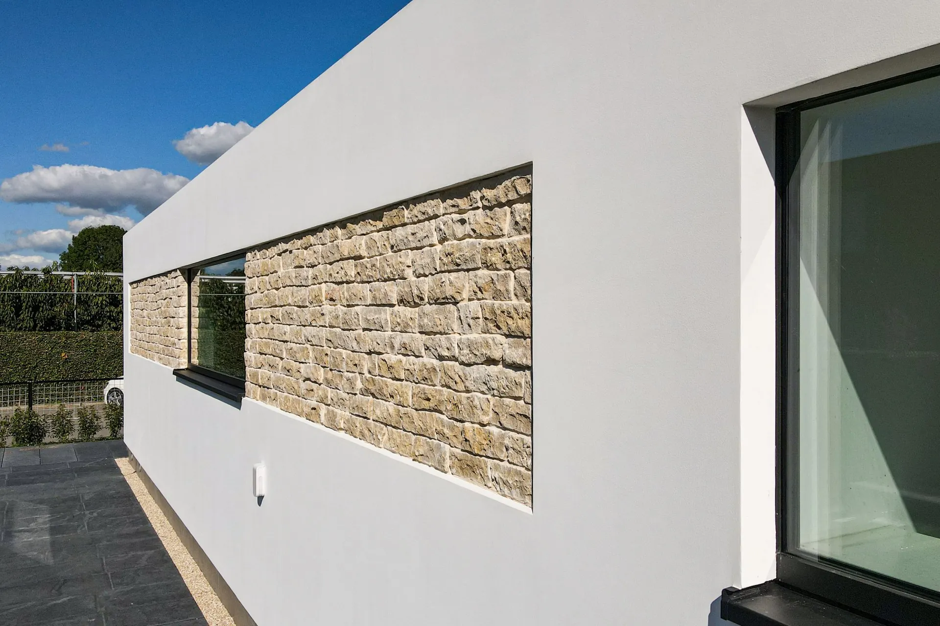 Detail van dezelfde villa: glad stucwerk rond een raam met een vlak van natuursteen
