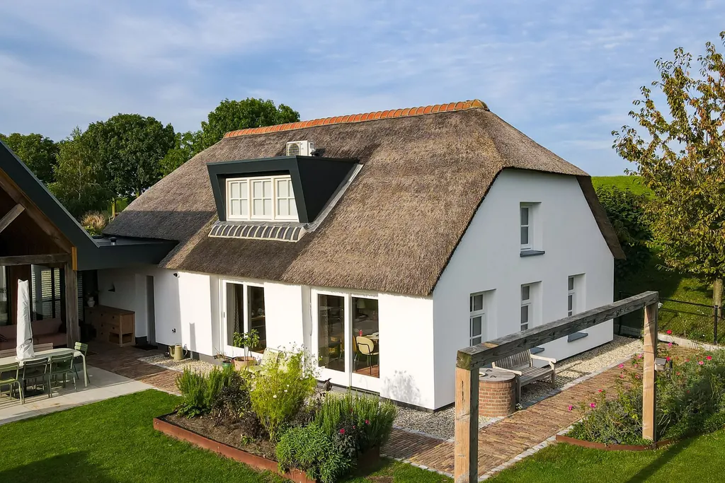 Woonboerderij in Hurwenen met rieten kap en witte gevels in een groene tuin