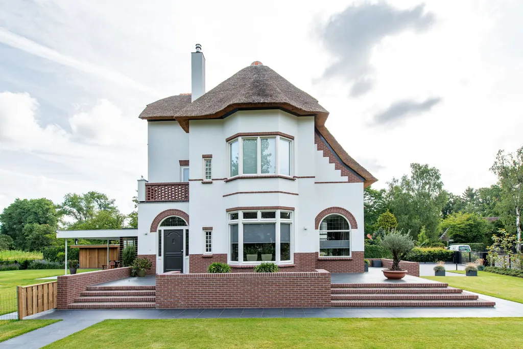 Klassieke villa in Oisterwijk met rieten kap, wit stucwerk en rode bakstenen accenten