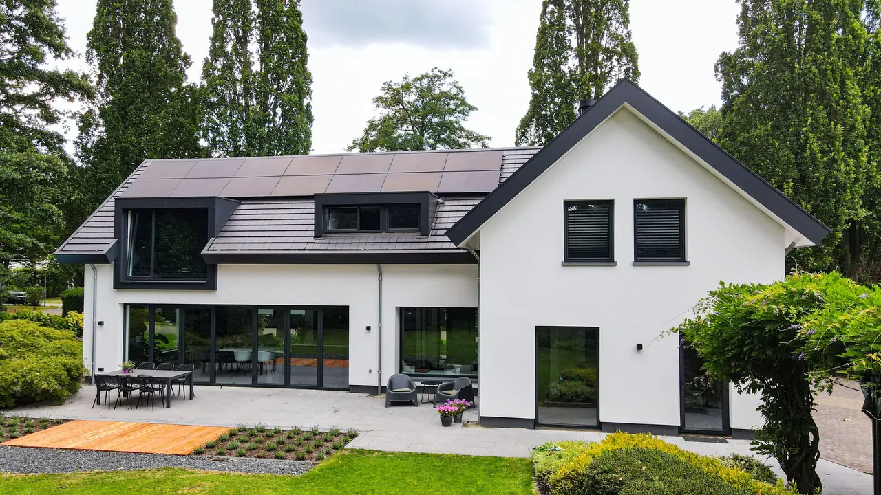 Wit gestucte villa met donkere dakkapellen en een groot terras